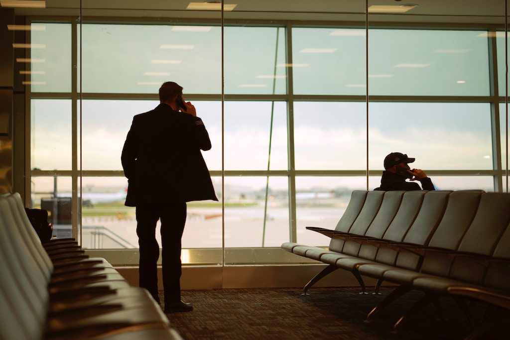 A stock photo of a businessman talking on his phone in an airport.