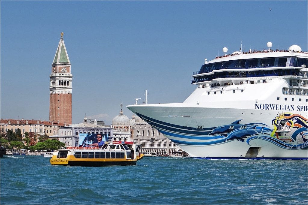 A cruise ship dwarfs a Venetian water taxi
