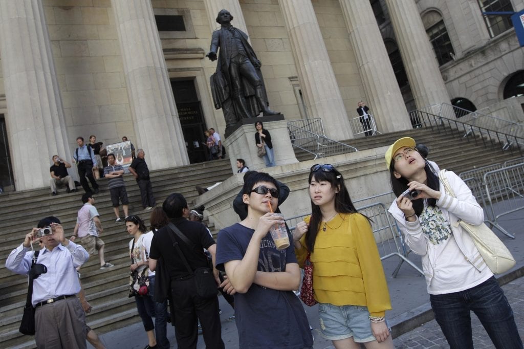 Chinese tourists take in the sights of the New York Stock Exchange and Federal Hall National Memorial. UK-based Thomas Group collapsed on Sunday, but the brand lives on in China and India.