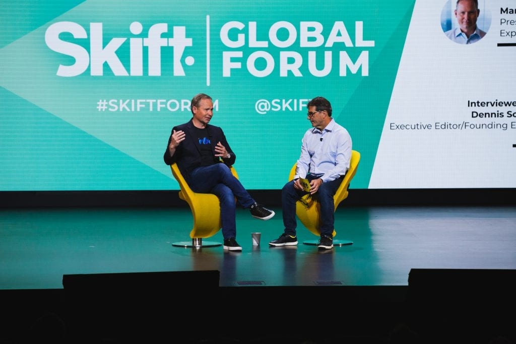 Shown here is a photo of Mark Okerstrom Expedia Group CEO and President speaking on-Stage at Skift Global Forum in New York on Thursday.