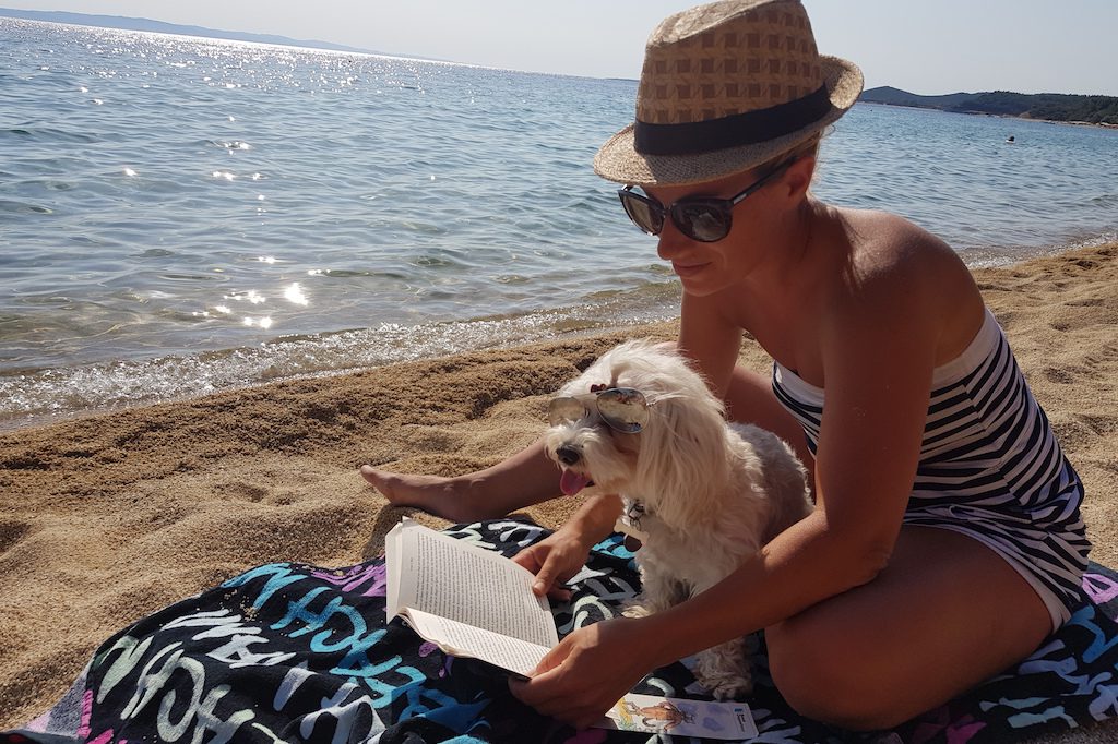 Andrea Mladin, founder of Pet Travel Advisor, on the beach with Mila, her Maltese puppy.