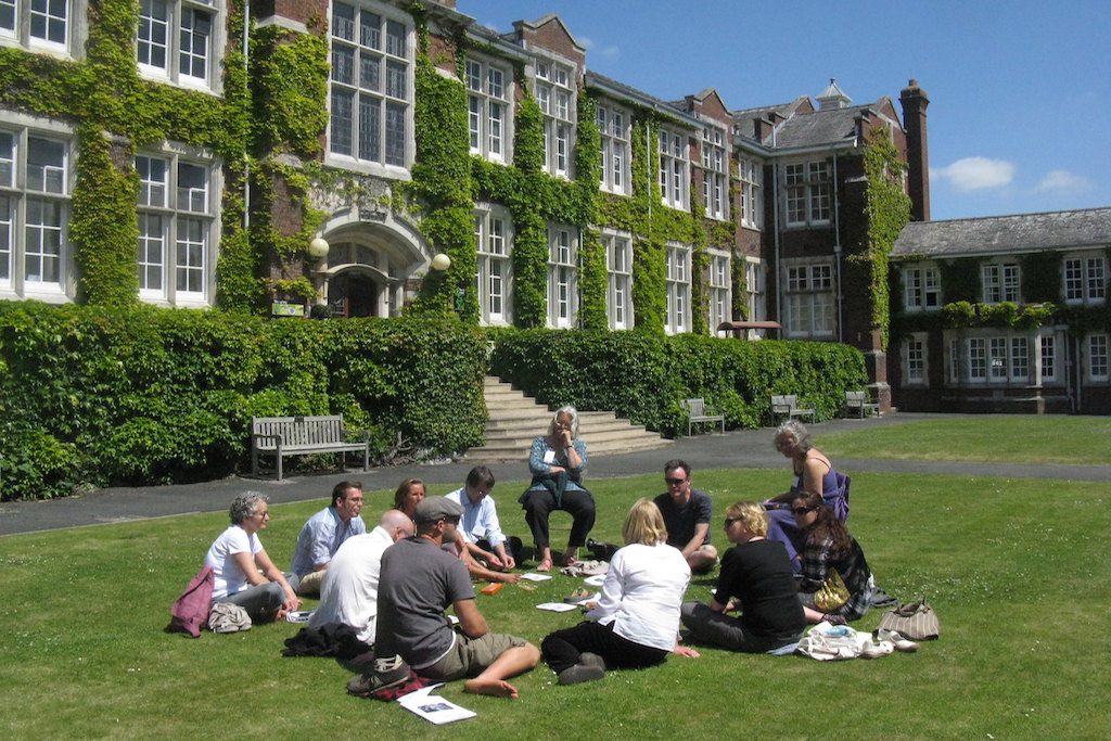 Attendees sit outside during an event at a former agricultural college in Devon, England. Increasingly, meeting planners are choosing sustainable locations and organizing activities focused on the environment. 