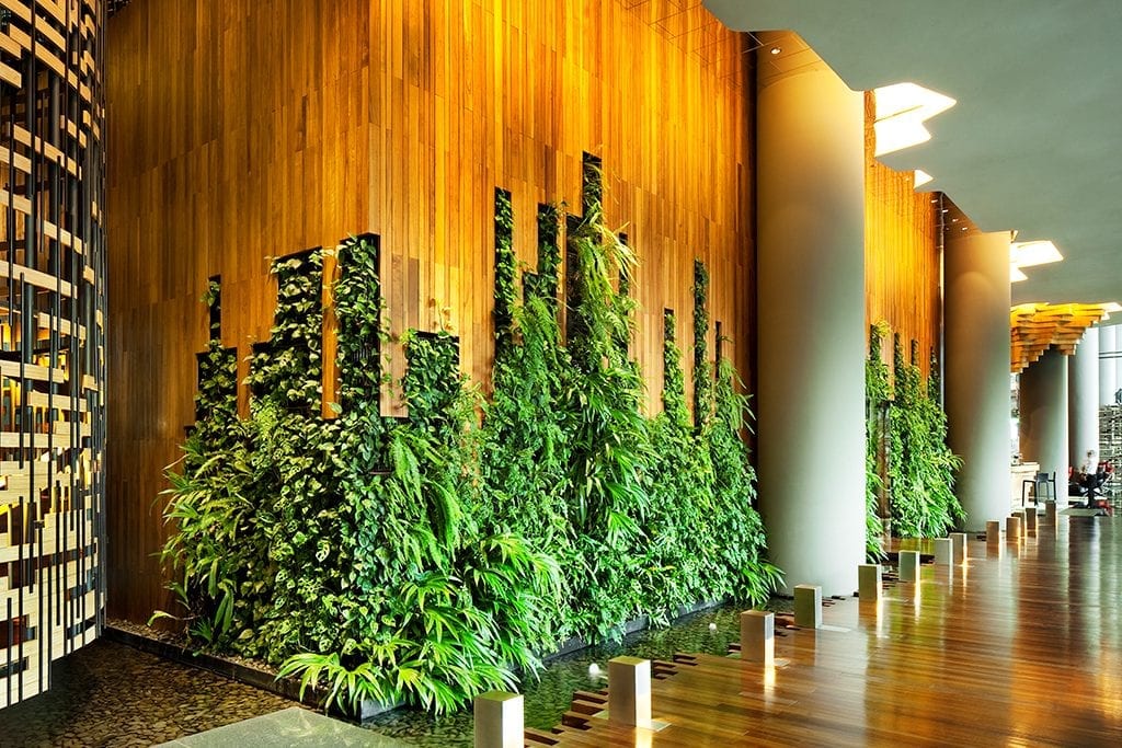 The PARKROYAL on Pickering in Singapore incorporates natural materials, curves, and greenery throughout its interior design. Biophilic design principals include bringing nature inside, like the living wall shown here.