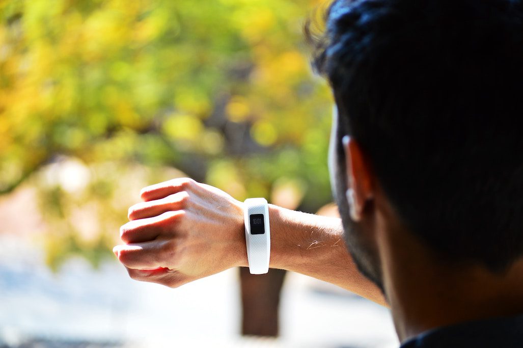 A man is wearing a Fitbit. Alphabet is reportedly in talks to acquire the wearable tracking brand.