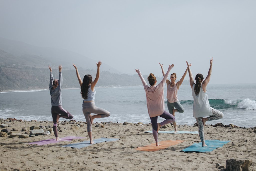 A yoga class takes place on a beach. The wellness industry continues to grapple with issues related to diversity and inclusion.