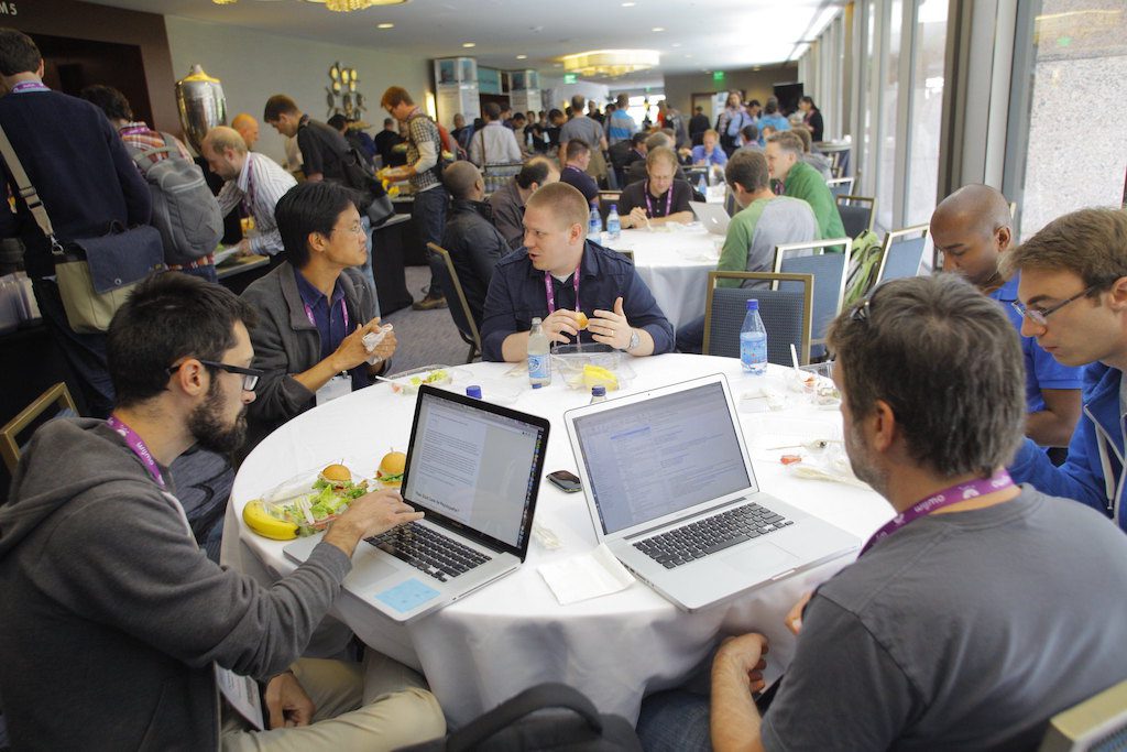 Attendees use their laptops in the dining area of an event. 