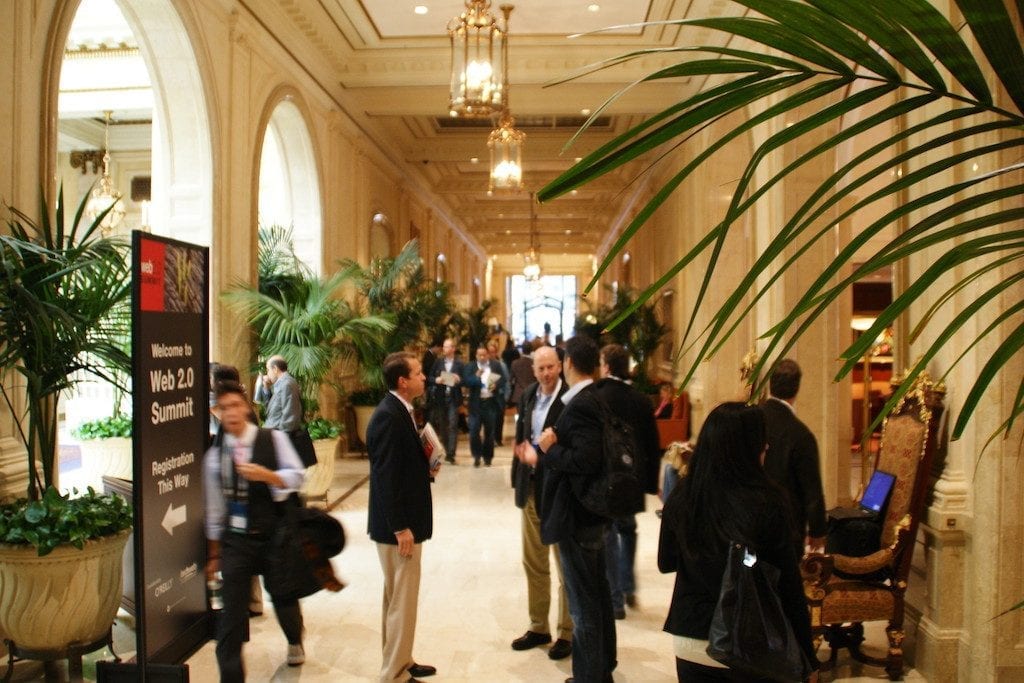 Conference attendees mingle in the halls of a hotel convention center. 