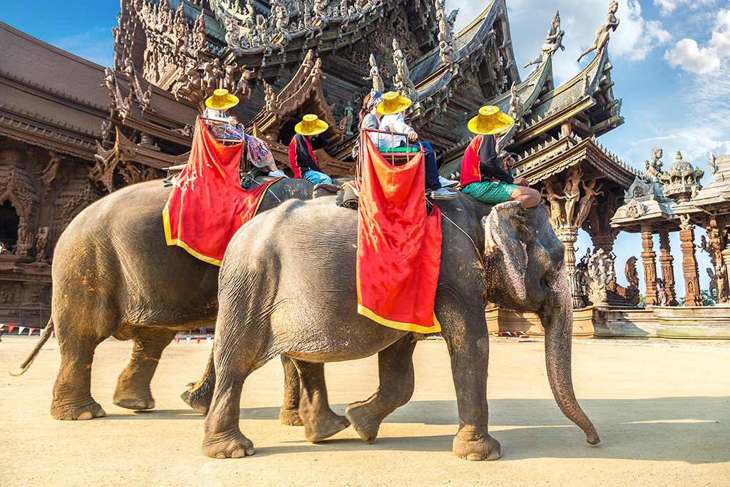Tourists ride Asian elephants around the Sanctuary of Truth in Pattaya, Thailand.