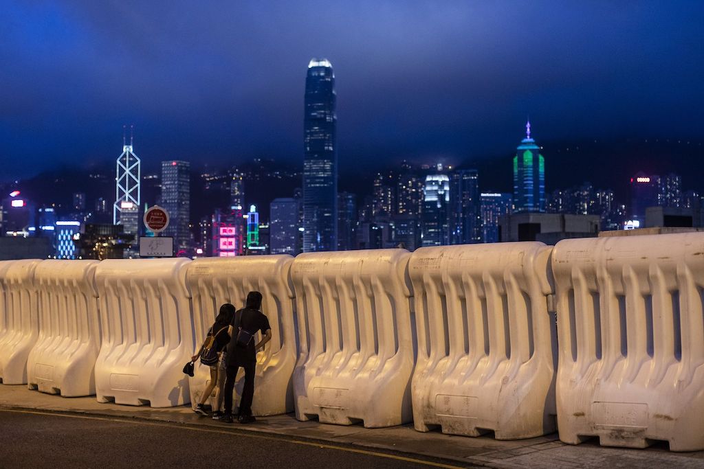 Demonstrators look through water barriers outside West Kowloon Station as the city skyline stands during a protest in Hong Kong.
