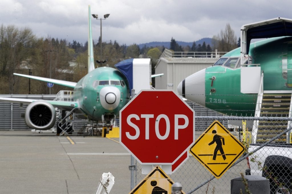 Shown here are Boeing 737 Max jets parked behind a stop sign indicating a traffic crossing at a Boeing Co. production facility in Renton, Wash. Boeing cut production of its troubled 737 Max.
