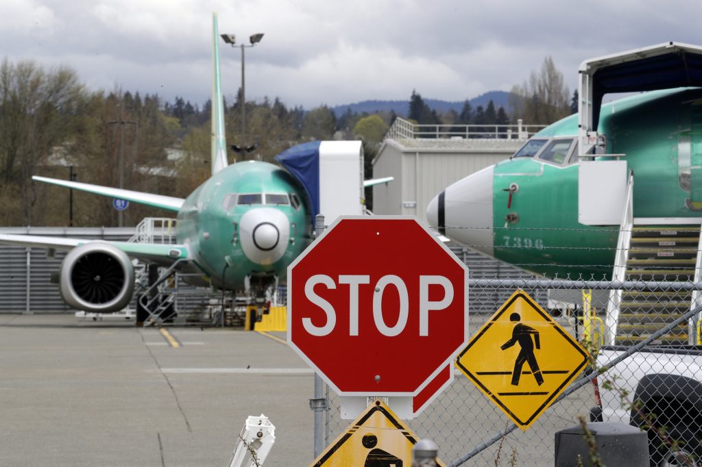 Shown here are Boeing 737 Max jets parked behind a stop sign indicating a traffic crossing at a Boeing Co. production facility in Renton, Wash. Boeing cut production of its troubled 737 Max.