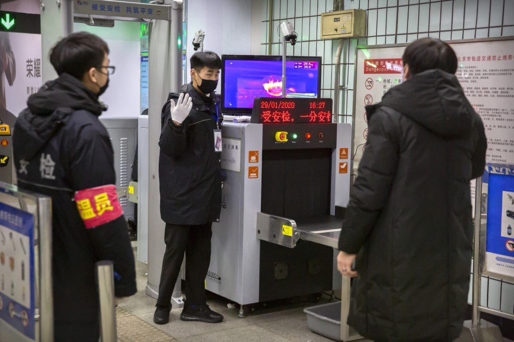Security officials in Beijing give instructions in the public transportation system amid the coronavirus outbreak. Travelers are on alert for coronavirus across the Asia-Pacific region.