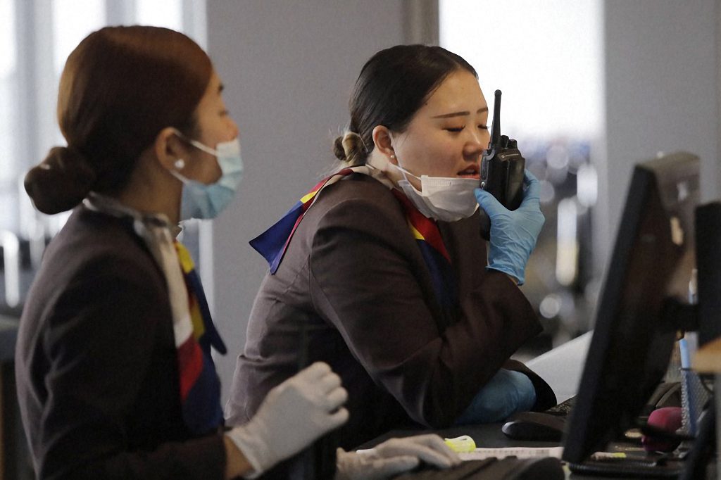 A gate agent pulls down her mask to speak on a radio at Seattle-Tacoma International Airport Tuesday, March 3, 2020, in SeaTac, Wash. 
