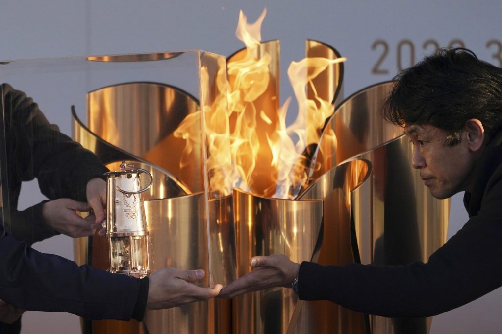 Officials light a lantern from the Olympic Flame at the end of a flame display ceremony in Iwaki, northern Japan, before the Olympics were postponed. 