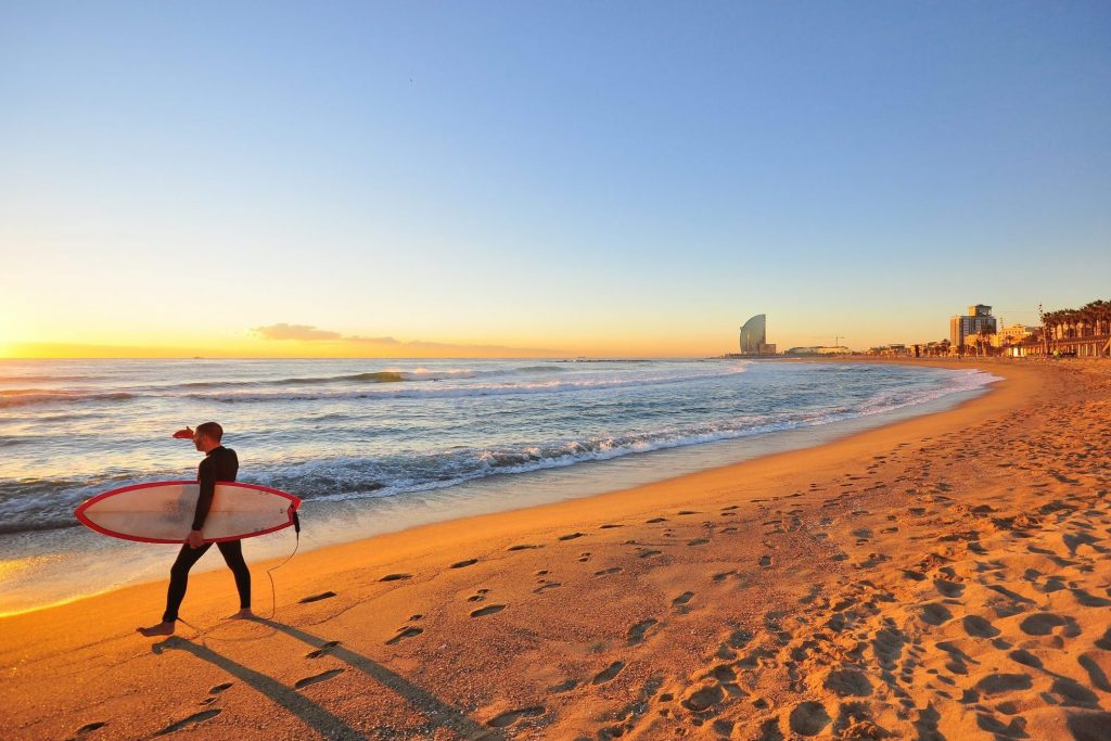 A file photo of a surfer at sunset on a Barcelona beach in Spain. Spain's tourism reopening June 7, 2021 was hurried and confusing to travelers.