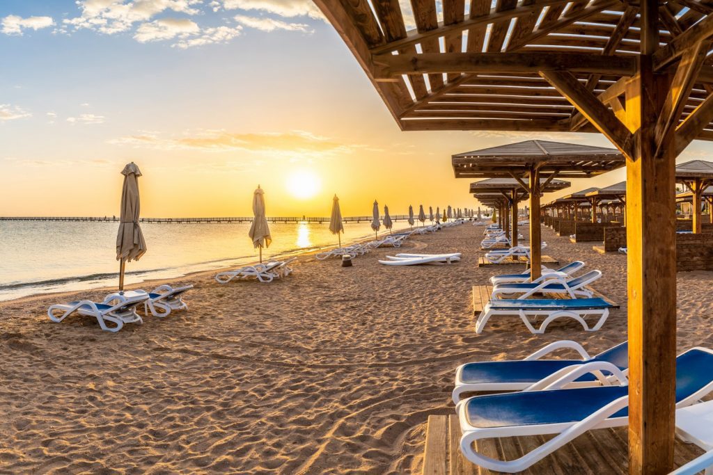 Landscape with sunbeds and umbrella on the Red Sea beach at sunrise in Hurghada, Egypt.