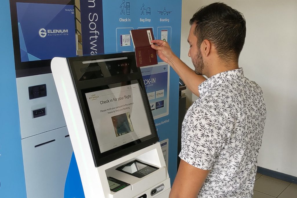 A person demonstrates a self-service kiosk from Elenium Automation that aims to help identify travelers with medical conditions.