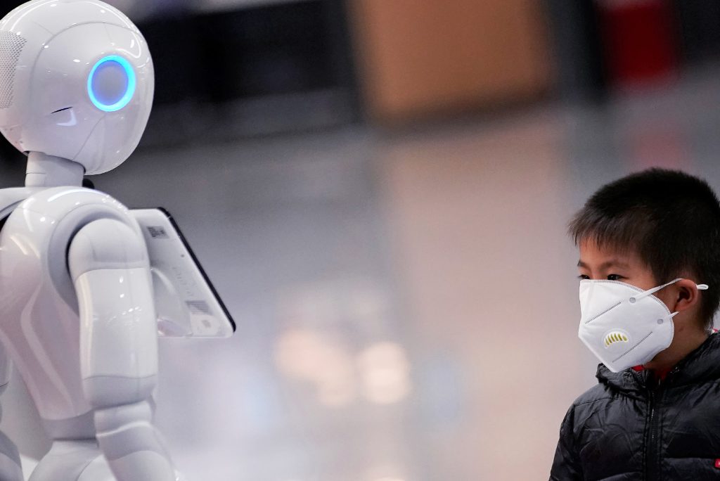 A boy watches a robot at Shanghai's Pudong International Airport as Chinese tech companies start to deploy their wealth, technological prowess and massive databases to help combat the coronavirus outbreak.