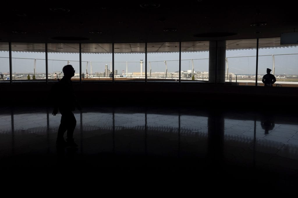 A traveler walks through an observation deck overlooking runways at the Haneda International Airport in Tokyo, April 3, 2020.