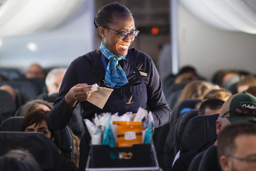 An Alaska Airlines flight attendant serves snacks during happier times. 