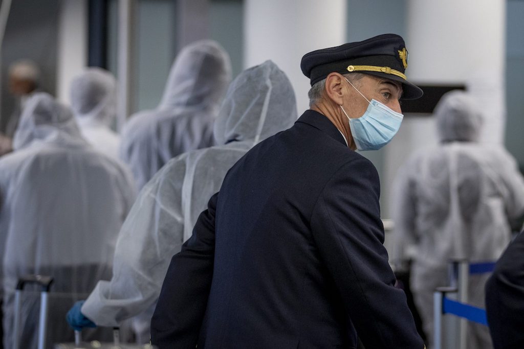 A pilot wearing a face-mask prepares to board an aircraft. 