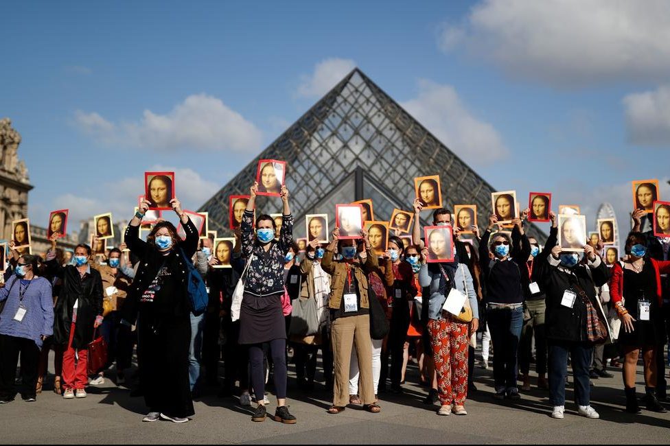 Paris tour guides hold posters depicting the Mona Lisa painting during an action at Le Louvre museum courtyard to warn on their working conditions.