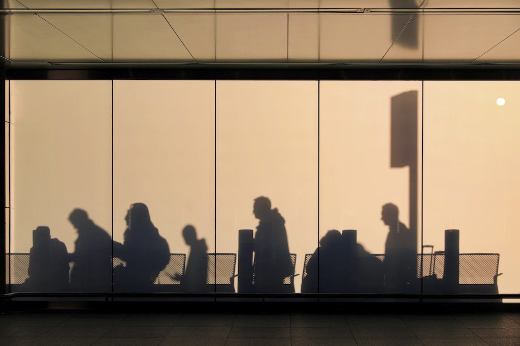 Travelers' shadows queue at Heathrow Airport.