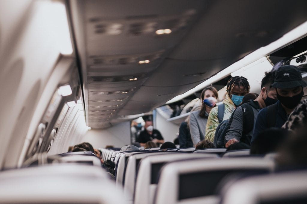 Passengers board a plane while wearing masks. The FAA is promising harsher penalties for passengers who defy rules. 