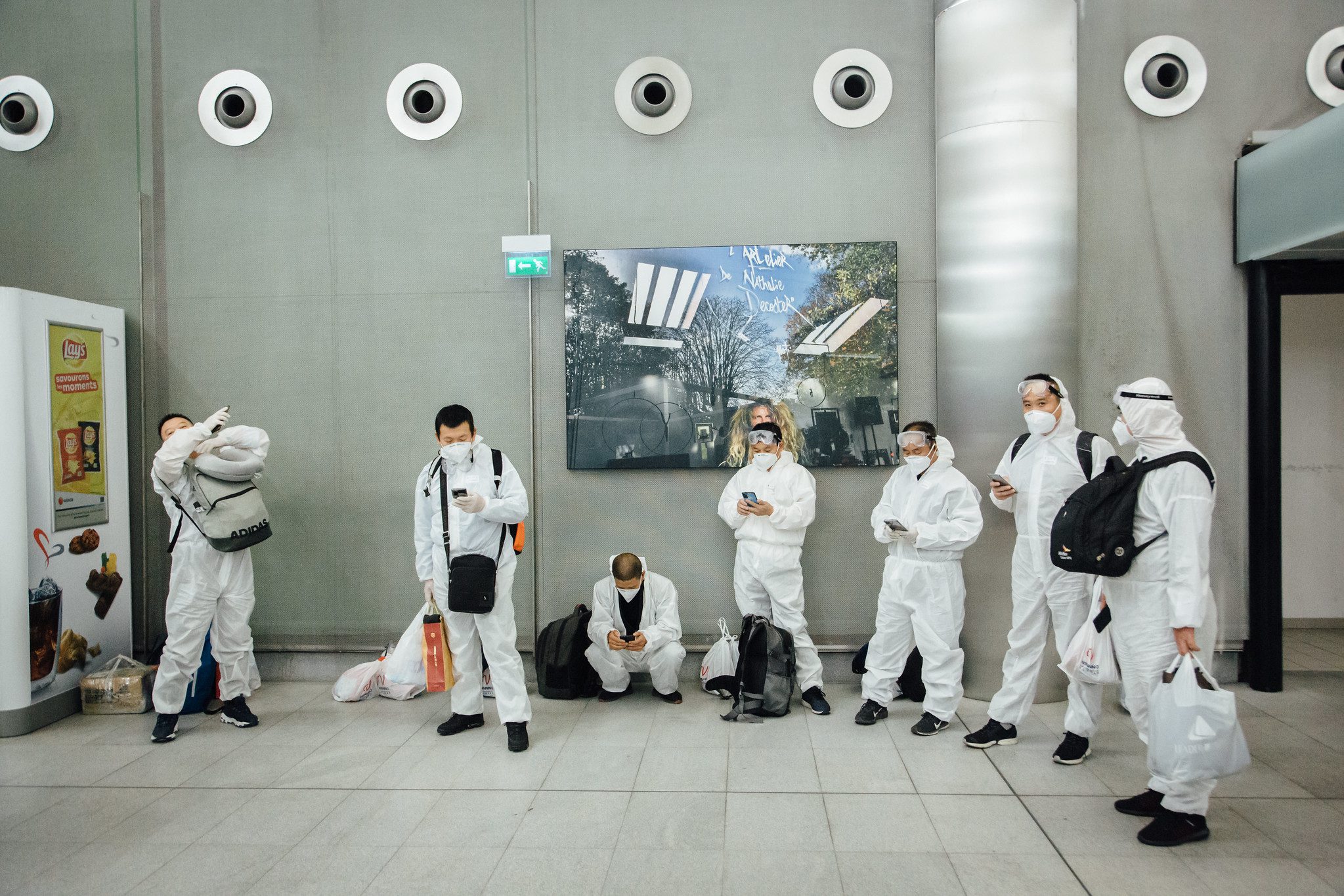 A group of Chinese tourists wear full protective suits against the COVID-19 virus wait at Roissy Charles de Gaulle Airport.