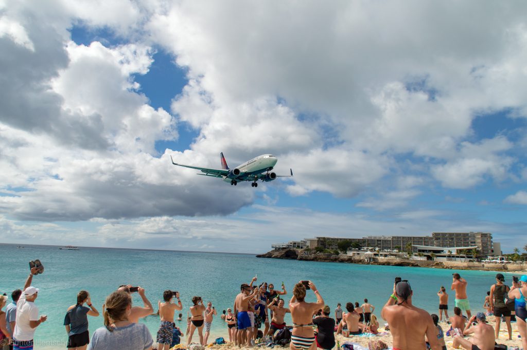 Tourists at a Philipsburg, St. Maarten beach taking photos of an incoming Delta flight.  
