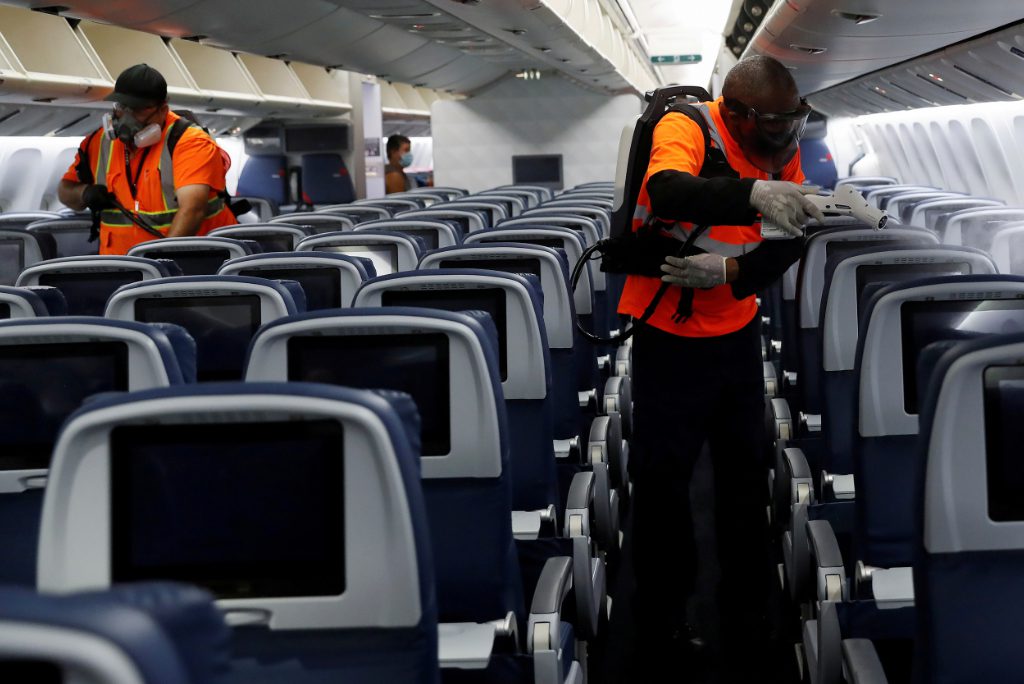 Delta Air Lines pre-flight cleaning crew members use electrostatic disinfection devices to clean an aircraft at JFK International Airport in New York in August 2020. The carrier said on Wednesday it will stop blocking middle seats as of May 1, a move that will allow it to start selling more seats.