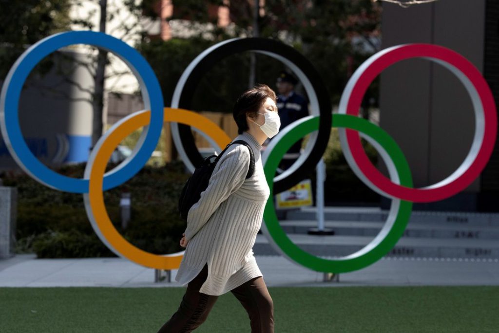 A woman walks past the Olympic rings in front of the Japan Olympics Museum, in Tokyo, in March 2020. 