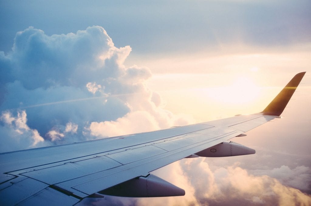 An aircraft flying through clouds carries passengers to their subscription travel destination. 