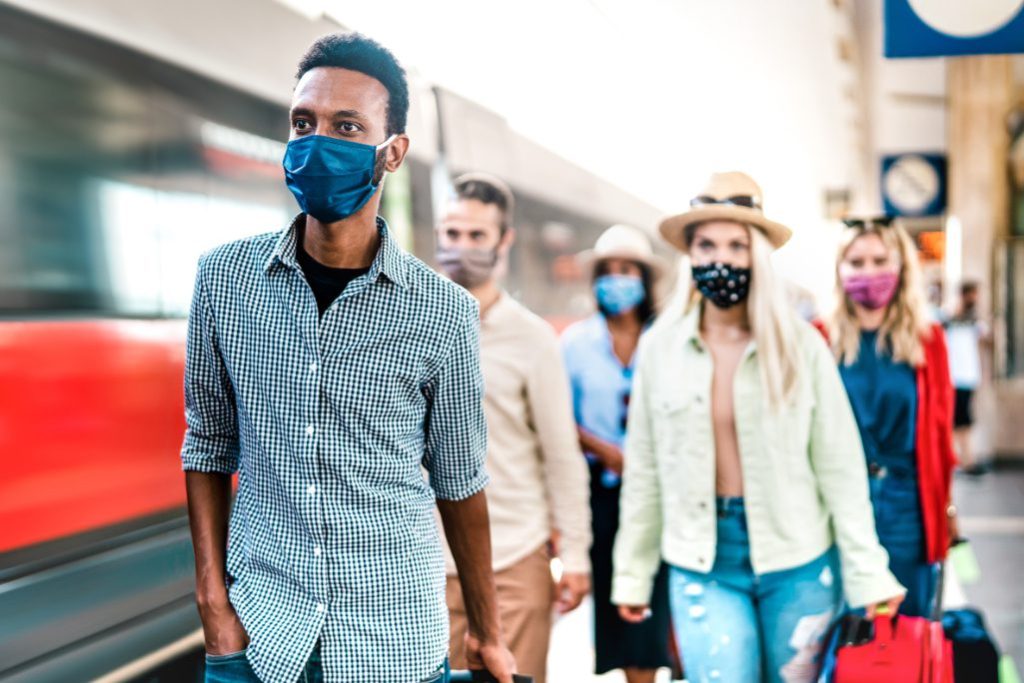 Multiracial crowd of people walking at railway station platform adobe