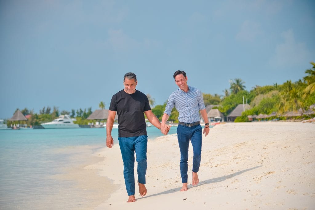 From left: Joel Cabrera, Chief Travel Officer and co-founder of Zoom Vacations, walking with his boyfriend Matt on the beach in the Maldives. 
