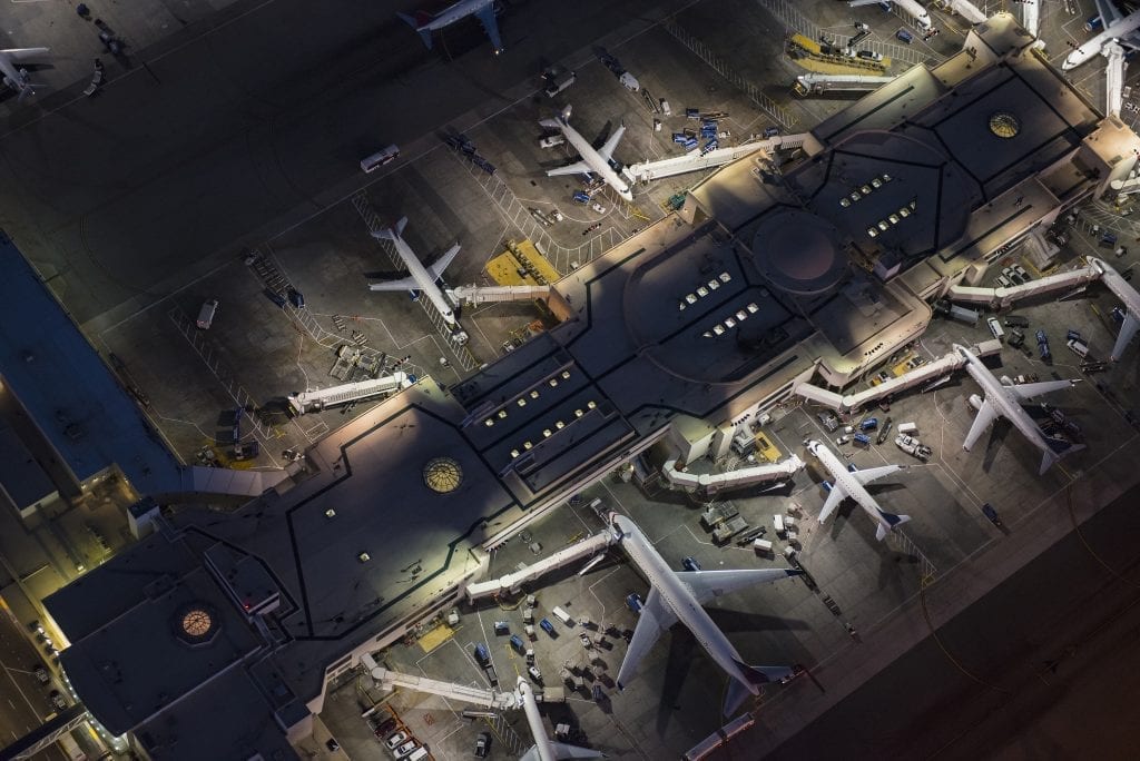 Aerial view of airplanes parked at airport gates awaiting passengers using pay when you fly to travel.  