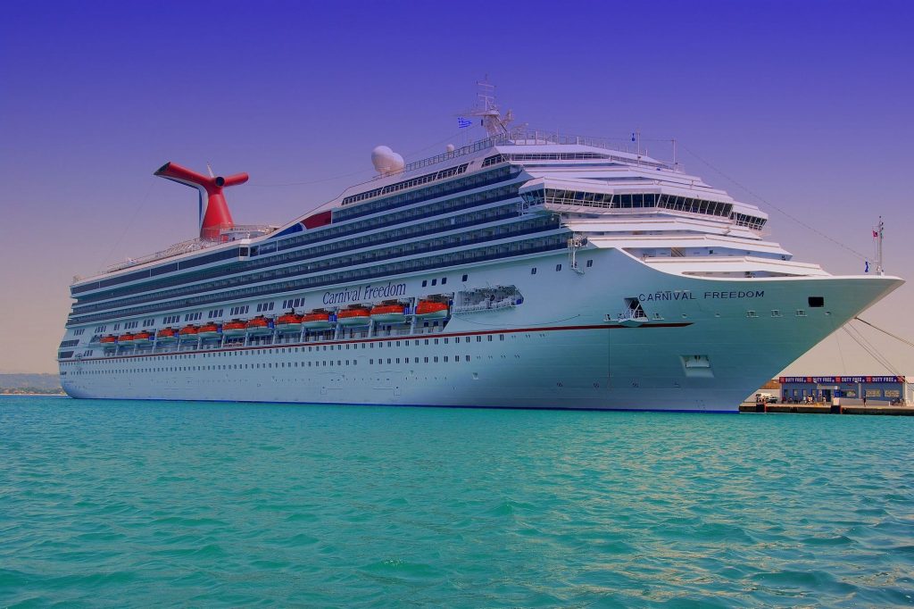 A Carnival Freedom cruise ship sits at a port waiting on passengers to sail. 