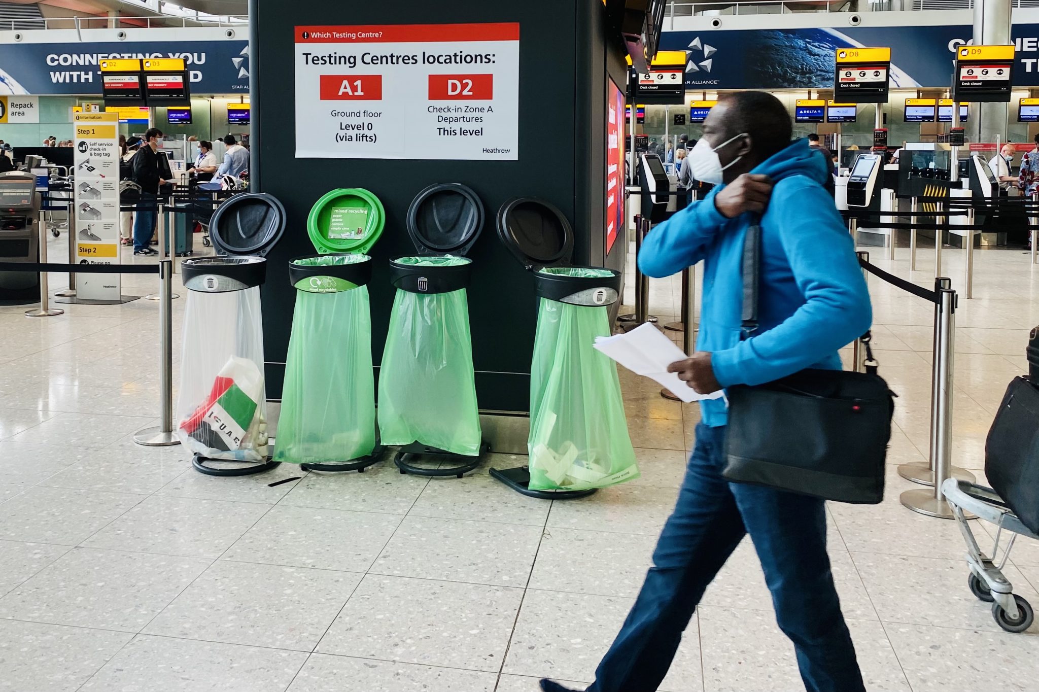 A passenger walking by signs for Covid testing centers at Heathrow Airport.
