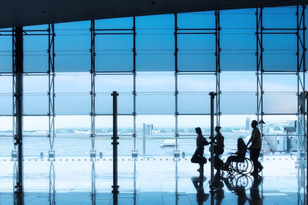 A passenger pushes a reduced mobility passenger through airport terminal