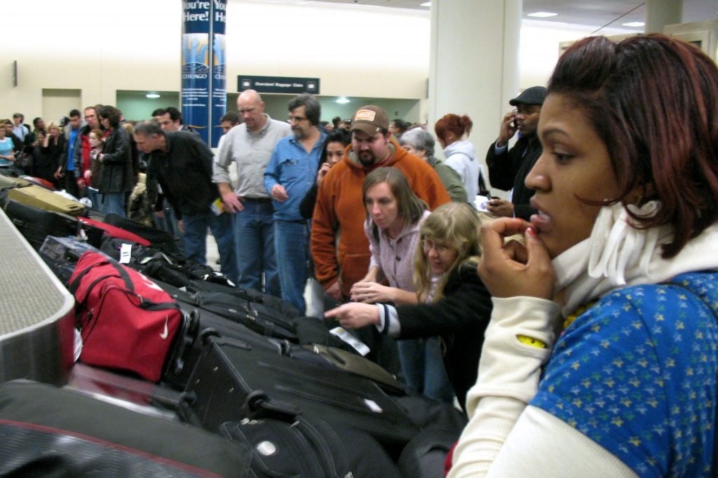 Passenger is worriedly looking for her checked luggage on the carousel. 