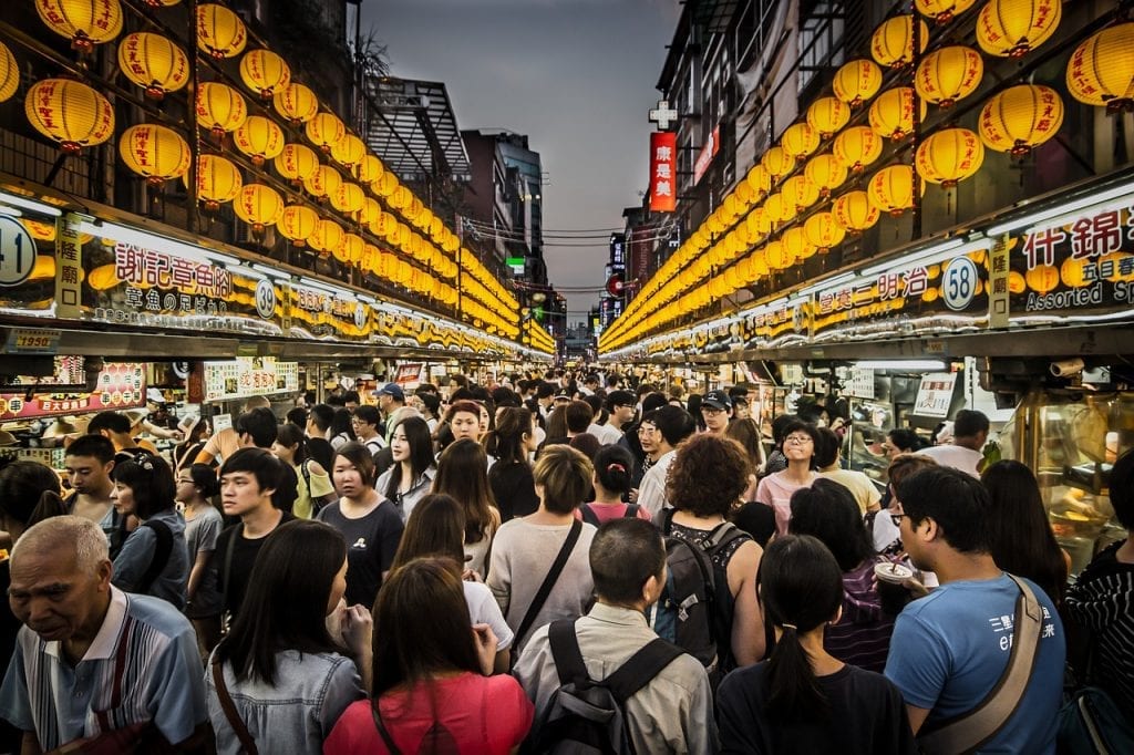 A horde of shoppers congregate in a night market to grab a bite to eat. 