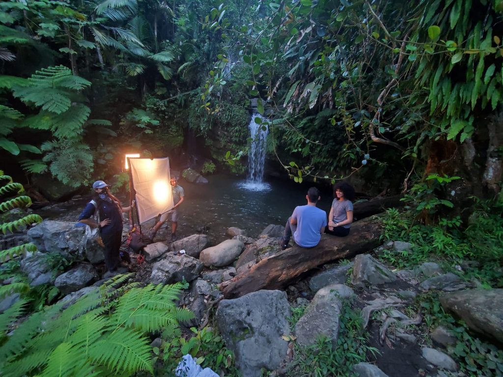 photo shoot of couple sitting on rocks and facing waterfall