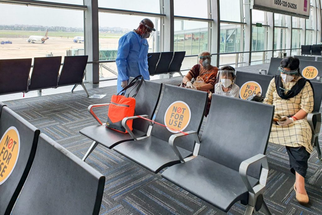 Netaji Subhas Chandra Bose International Airport, Calcutta, India. Family members maintaining social distancing in protective gear before boarding flight at airport.