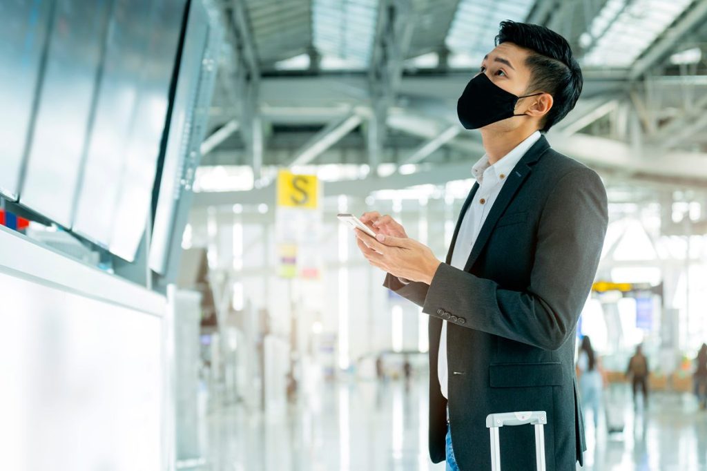 man checking flight board at airport