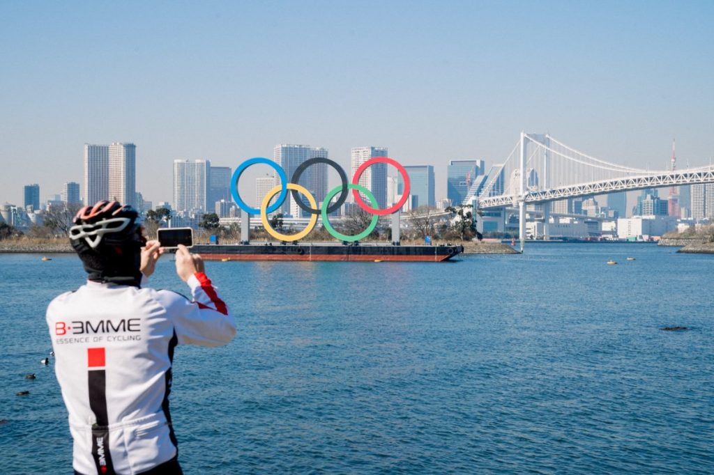 view of cyclist photographing view of olympic rings monument over Tokyo bay