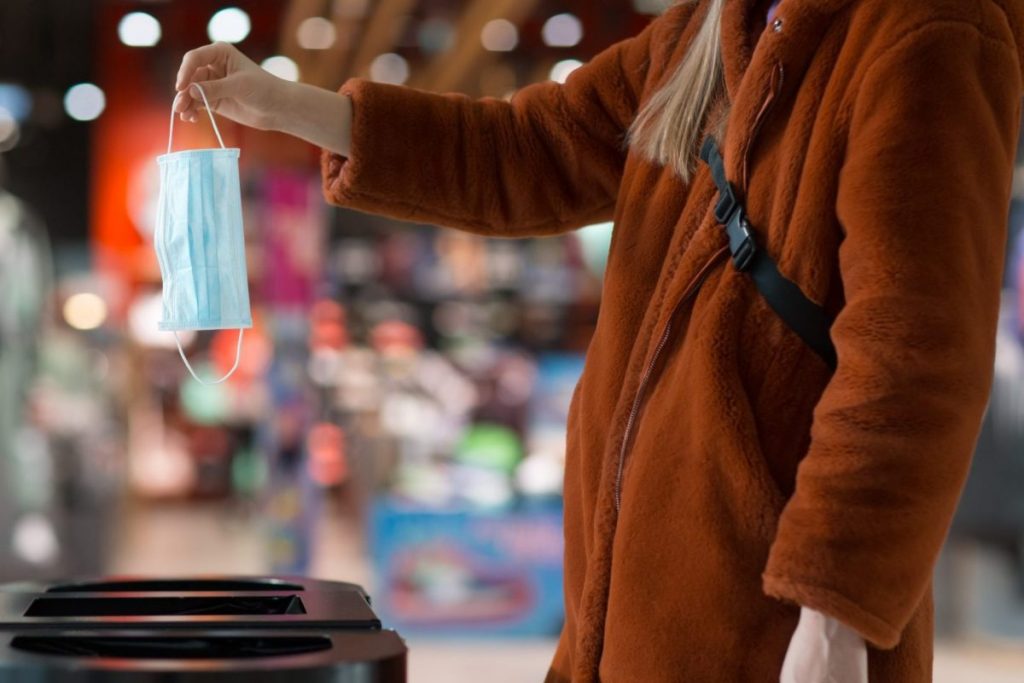 Woman tossing out a face mask.