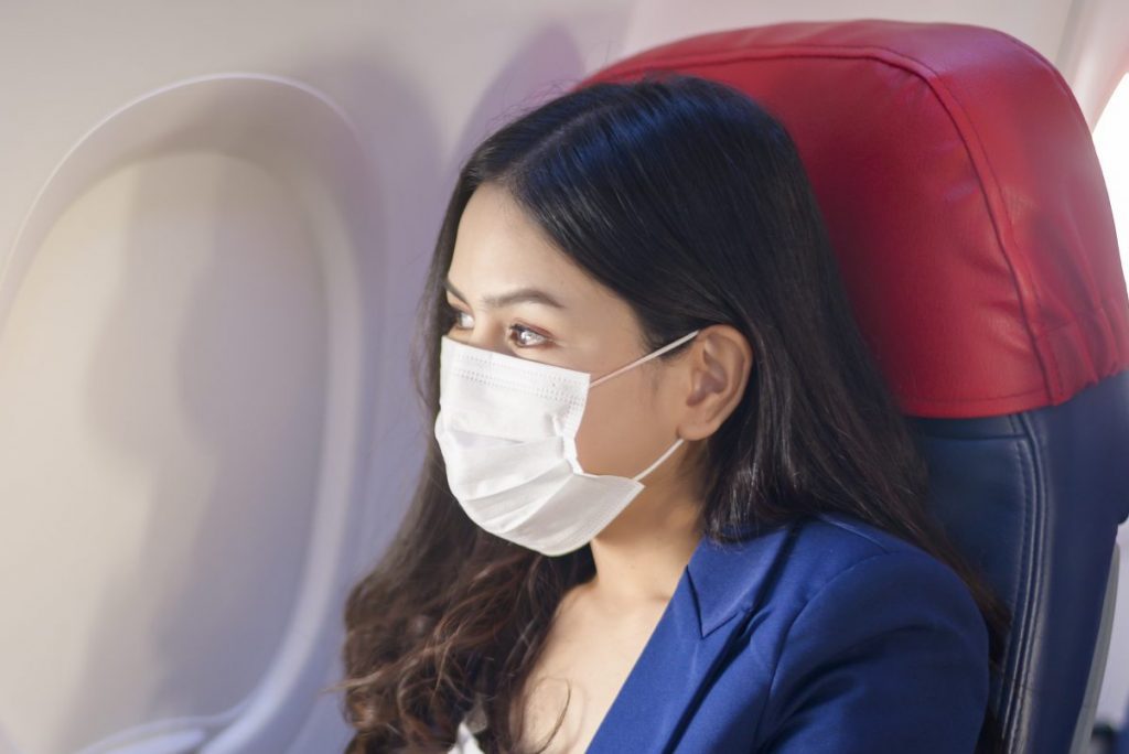 A businesswoman wearing a mask while traveling a plane