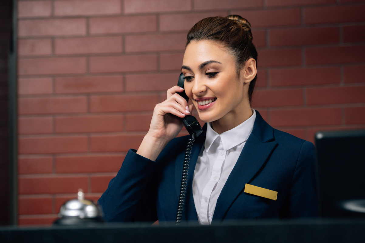 Hotel receptionist receiving call at workplace. Source: LightFieldStudios via Getty Images.