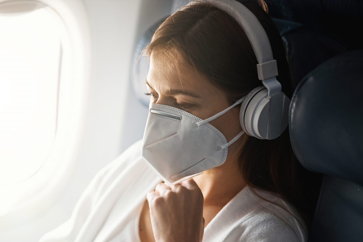 A traveler is wearing a mask on a plane