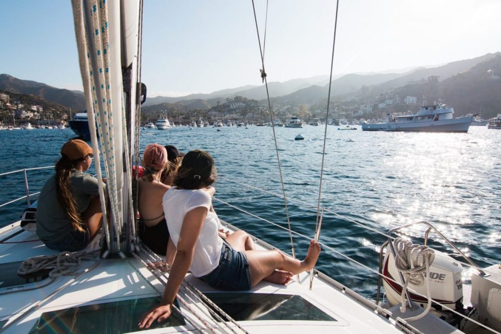 Friends sitting on the front of a yacht overlooking the water